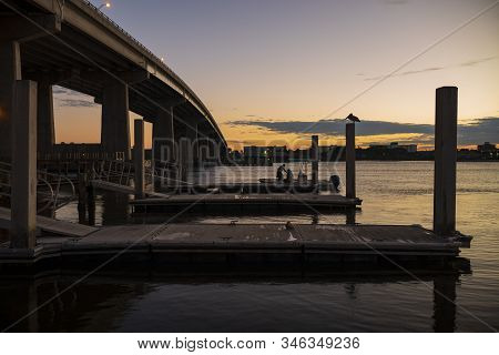 Silhouetted People Boarding A Boat For A Fishing Trip, Off A Pier In The Halifax River In Daytona Be