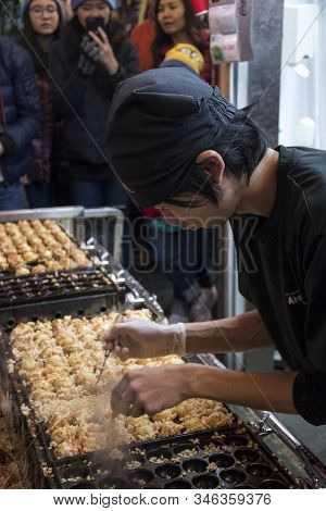 Osaka, Japan- 27 Nov, 2019: Vendor Making Takoyaki On A Takoyaki Pan In Osaka, Japan. Takoyaki Is Fa