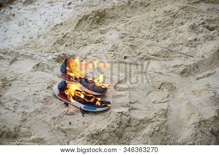 Burning Sports Sneakers Or Gym Shoes On Fire Stand On Sandy Beach Coast. Athlete Burned Out. Physica