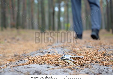 Young Man Loses His Keys Bunch On Russian Autumn Fir Wood Path. Carelessness And Losing Keys Concept