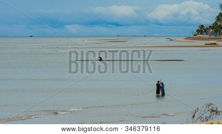 Two Fishermen Standing In The Water At Low Tide Fisihing With A Net In Pak Nam Pran Thailand