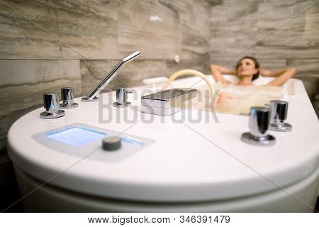 Beautiful Woman Relaxing In The Bathtub Having A Hydromassage Therapy. Focus On The Bath