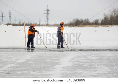 Workers Rafting Ice Blocks Along A Channel Cut Out By A Frozen Lake