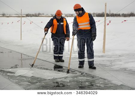 Workers Rafting Ice Blocks Along A Channel Cut Out By A Frozen Lake