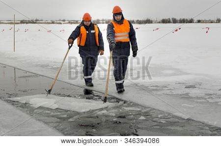 Workers Rafting Ice Blocks Along A Channel Cut Out By A Frozen Lake