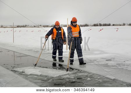 Workers Rafting Ice Blocks Along A Channel Cut Out By A Frozen Lake