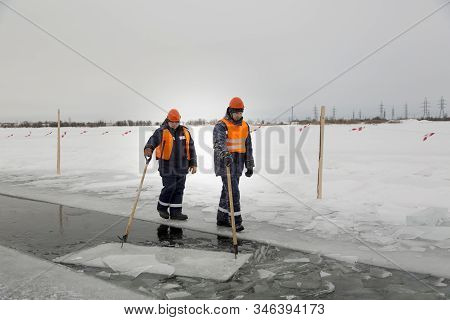Workers Rafting Ice Blocks Along A Channel Cut Out By A Frozen Lake