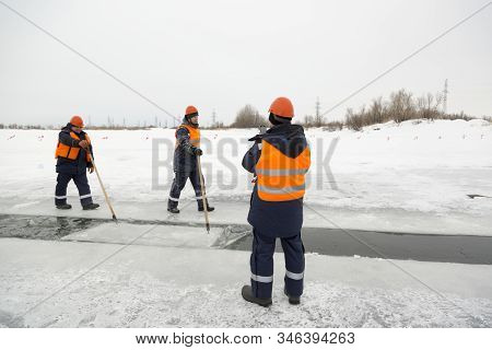 Workers Rafting Ice Blocks Along A Channel Cut Out By A Frozen Lake