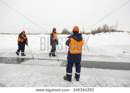Workers Rafting Ice Blocks Along A Channel Cut Out By A Frozen Lake