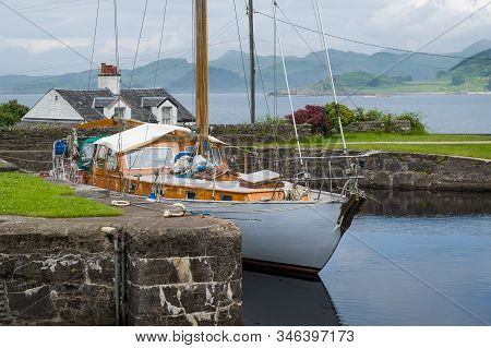 Sailing Boat With White Hull And Old Wooden Deck And Masts Docked At Crinan, Scotland.