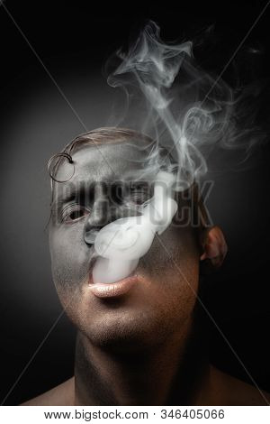 Close-up Portrait Of A Handsome Guy In Makeup Blows Smoke. Stock Art Photo Of A Smoker.