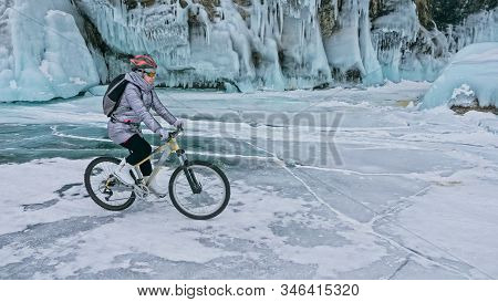 Woman Is Riding Bicycle Near The Ice Grotto. The Rock With Ice C