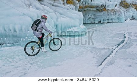Woman Is Riding Bicycle Near The Ice Grotto. The Rock With Ice C