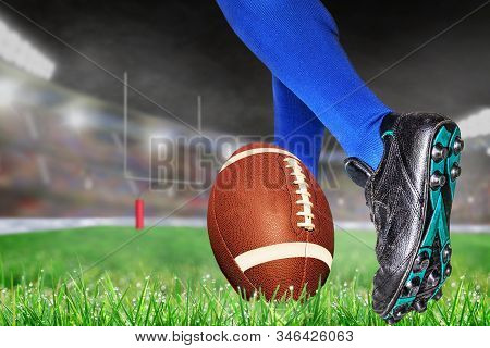 American Football Player Prepares To Kick Ball For Conversion Points Or Field Goal In Brightly Lit O