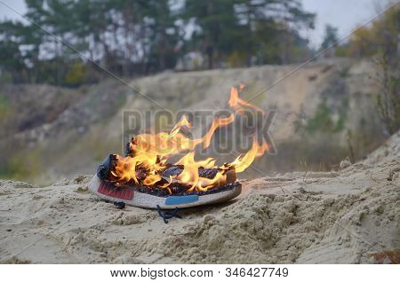 Burning Sports Sneakers Or Gym Shoes On Fire Stand On Sandy Beach Coast. Athlete Burned Out. Physica