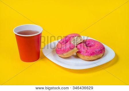 Two Sweet Half-eaten Pink Doughnuts On A White Plate Isolated On A Yellow Background. Red Disposable