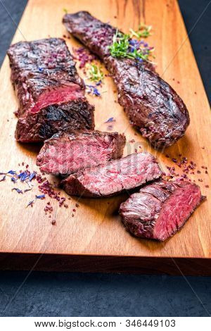 Barbecue dry aged venison tenderloin fillet steak natural with herbs and salt offered as closeup modern design wooden board 