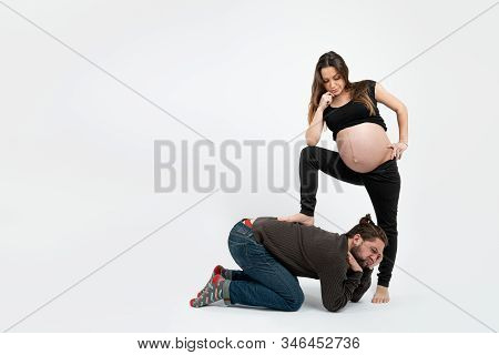 Displeased Young Bearded Man In Casual Clothes Leaned On His Hands, His Attractive Pregnant Wife In 