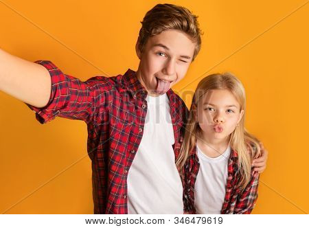 Playful Kids Taking Selfie, Little Brother And Sister Making Funny Faces And Fooling Together While 