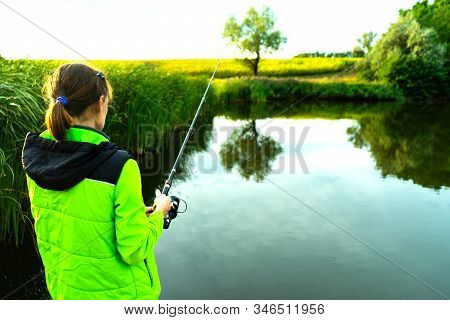 The Girl Is Fishing Using A Spinning Rod. Fishing In The Summer.