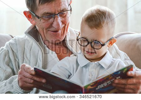Grandfather And Grandson Are Reading A Book