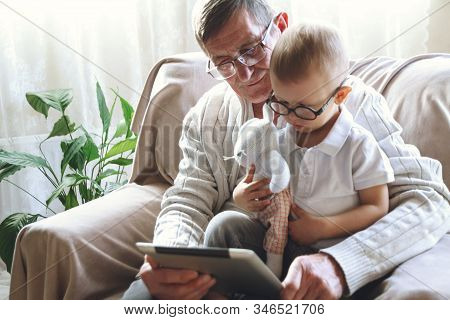 Elderly Grandfather And His Little Grandson Use A Tablet Device