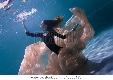 Young Slender Girl Underwater With A Cloth. Water Magic. Underwater Photography. Art