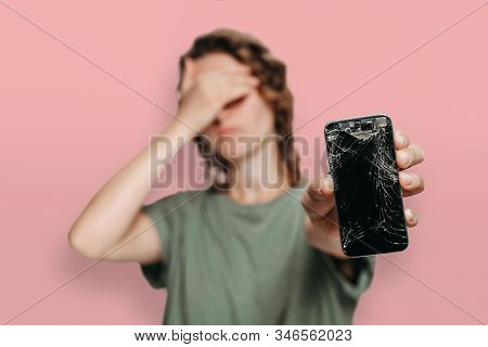 Upset Young Woman Holding Her Broken Smartphone In Her Hand. Phone Screen Need To Repair. Isolated O