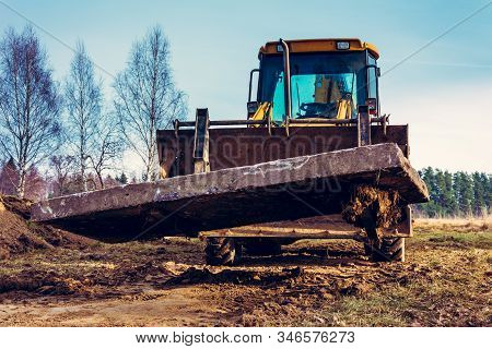 The Yellow Excavator Transports Concrete Slabs In The Countryside.