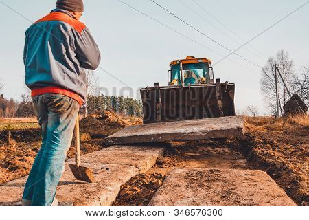 The Yellow Excavator Transports Concrete Slabs In The Countryside.