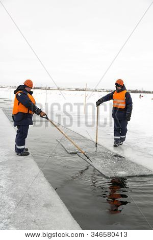Workers Rafting Ice Blocks Along A Channel Cut Out By A Frozen Lake