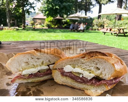 Close Up Of A Cross-section Of A Proscuitto, Cheese And Tomato Sandwich On Sourdough Bread On A Rust
