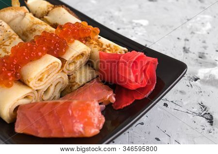 Pancakes Twisted Into A Tube With Red Fish, Red Caviar And Ginger On A Concrete Background