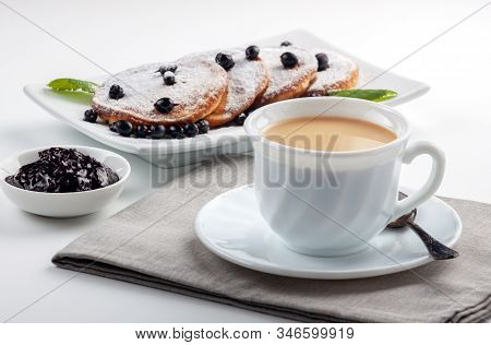 A Cup Of Coffee With Milk And A Plate With A Pancakes Is On The Table.