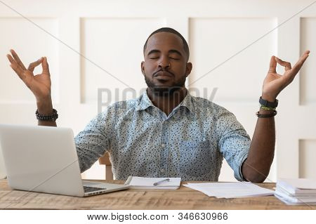 African Man Sitting At Desk Meditating During Workday At Workplace