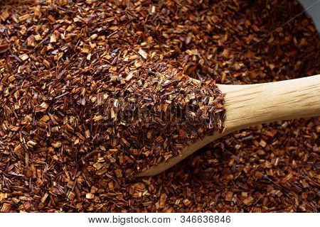Close Up (macro) Of Rooibos Or Redbush Tea Leaves; Being Lifted From A Bowl With A Wooden Spoon.