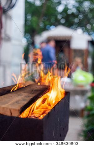 B-b-q Outdoors Background. Kindling Wood Barbecue Outdoors With Open Flame Against The Background Of