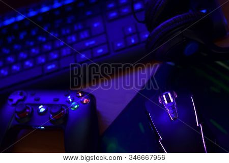 Modern Gamepad And Gaming Mouse Lies With Keyboard And Headphones On Table In Dark Playroom Scene. V