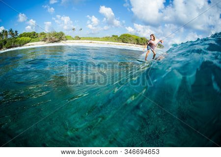 HURAA / MALDIVES - MARCH 22, 2019: Young surfer rides the ocean wave at the Honkeys surf spot in Maldives