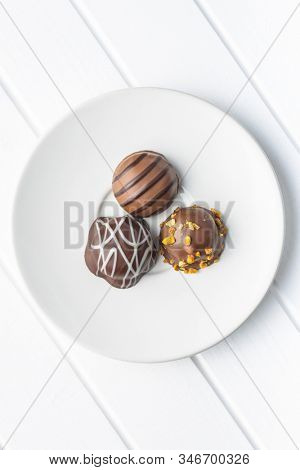 Praline bonbons. Chocolate truffles on plate on white table. Top view.