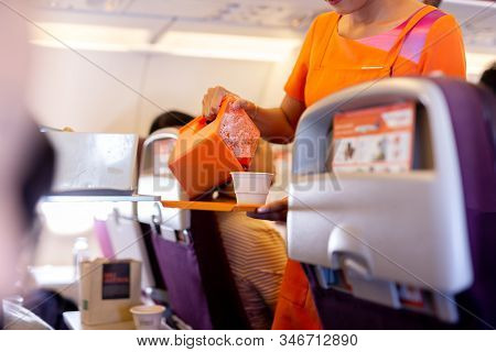Flight Attendant Serving Drinks To Passengers On Board.