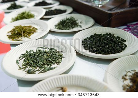 Green, Red And Black Tea, Sprinkled On Several Paper Plates. Demonstration Sample On A Showcase.