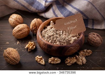 Walnut flour in the wooden bowl and whole seeds