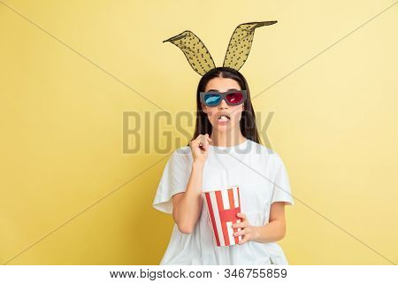 Watcing Cinema With Popcorn. Caucasian Woman As An Easter Bunny On Yellow Background. Happy Easter G