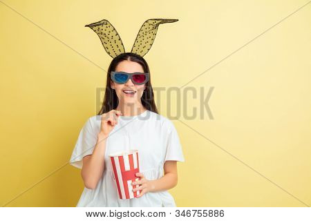 Watcing Cinema With Popcorn. Caucasian Woman As An Easter Bunny On Yellow Background. Happy Easter G