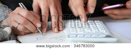 Close-up Of Couple Sitting At Home And Summing Up Expenses. Calculator For Precise Estimates Of Inco