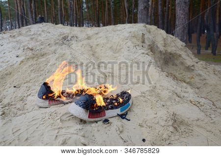 Burning Sports Sneakers Or Gym Shoes On Fire Stand On Sandy Beach Coast. Athlete Burned Out. Physica
