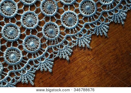 Diagonal Edge Of Light Blue Crochet Lace On Wooden Table