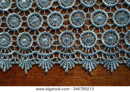 Horizontal Edge Of Light Blue Crochet Lace On Wooden Table