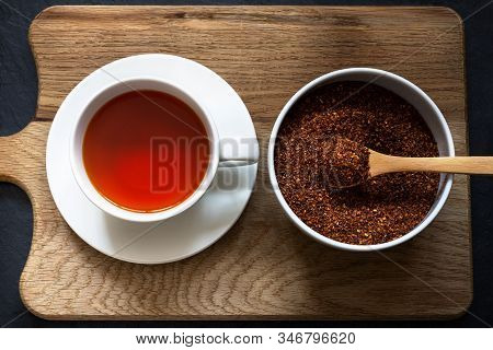 Overhead Shot Of A Cup And Saucer Containing Rooibos (redbush) Tea With White Bowl Of Leaves Scooped